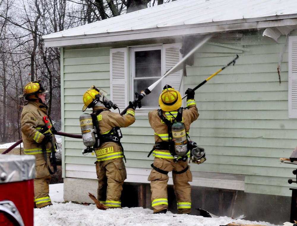 Firefighters pull away siding and spray water into a burning home on Oak Street in Oakland on Thursday.