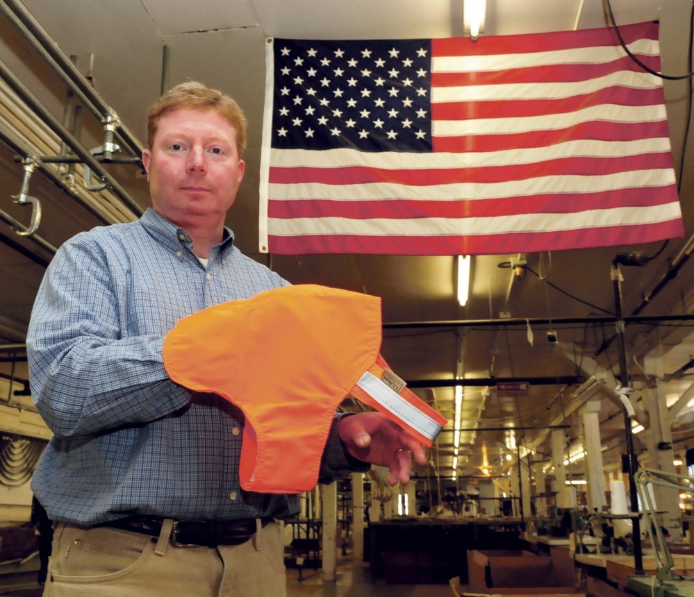 Bill Swain, owner of Maine Stitching Specialties in Skowhegan, holds a LL Bean No Fly Zone dog vest in Skowhegan in March 2015. The company recently got a contract with Walmart, which will sell the vests in its pet department for six months.