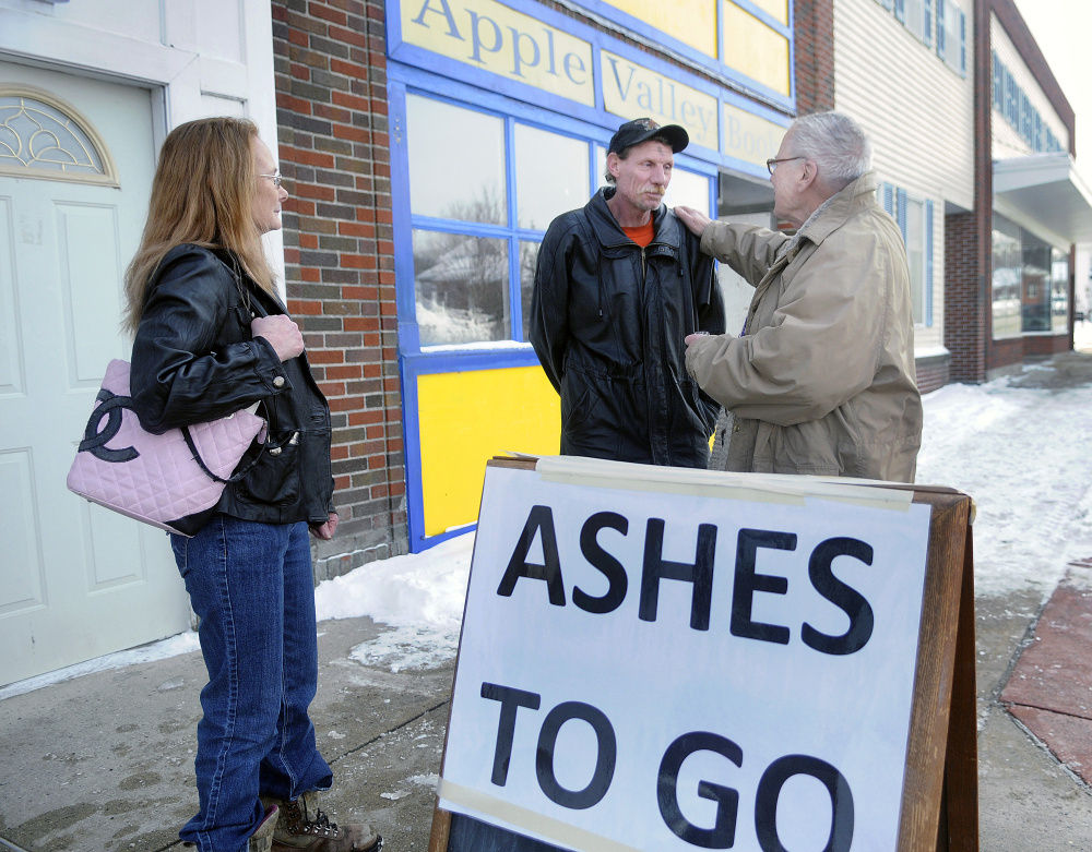 The Rev. James Gill speaks with Don Ladson Wednesday after applying ashes to him and Lori Audette on Main Street in Winthrop.