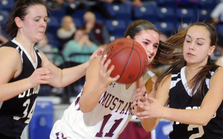 Staff photo by Andy Molloy 
 Monmouth's Hannah Anderson, center, grabs the ball from St. Dominic's Abigail Castonguay, left, and Rileigh Stebbins during a Class C South quarterfinal Monday at the Augusta Civic Center. Anderson scored a game-high 26 points to lead the Mustangs past the Saints, 51-39.