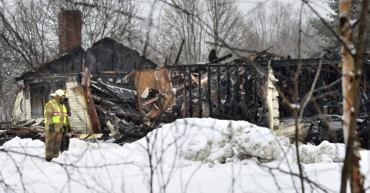 Firefighters work outside the burned remains of a home Wednesday on Pease Hill Road in Anson. Investigators say the fire was set intentionally to cover up a break-in at the property.