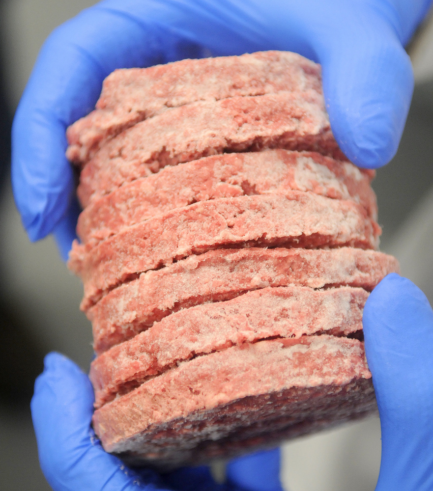 Butcher Moe Howard holds hamburg patties that were frozen in the flash freezer tunnel Monday at Central Maine Meats in Gardiner.