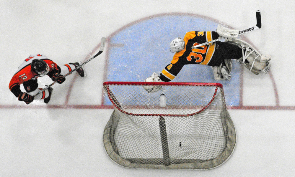Gardiner forward Tristan Hebert, left, scores a goal on Cape Elizabth goalie Grant Rusk to put Gardiner up 3-0 with 9:50 left in second period of a Class B South semifinal Friday at the Androscoggin Bank Colisee in Lewiston.