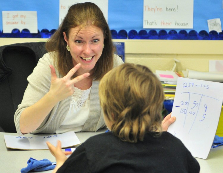 Katie Conway, a second-grade teacher in Readfield, works with a student. The bill to raise teachers’ minimum salary also would raise academic requirements.