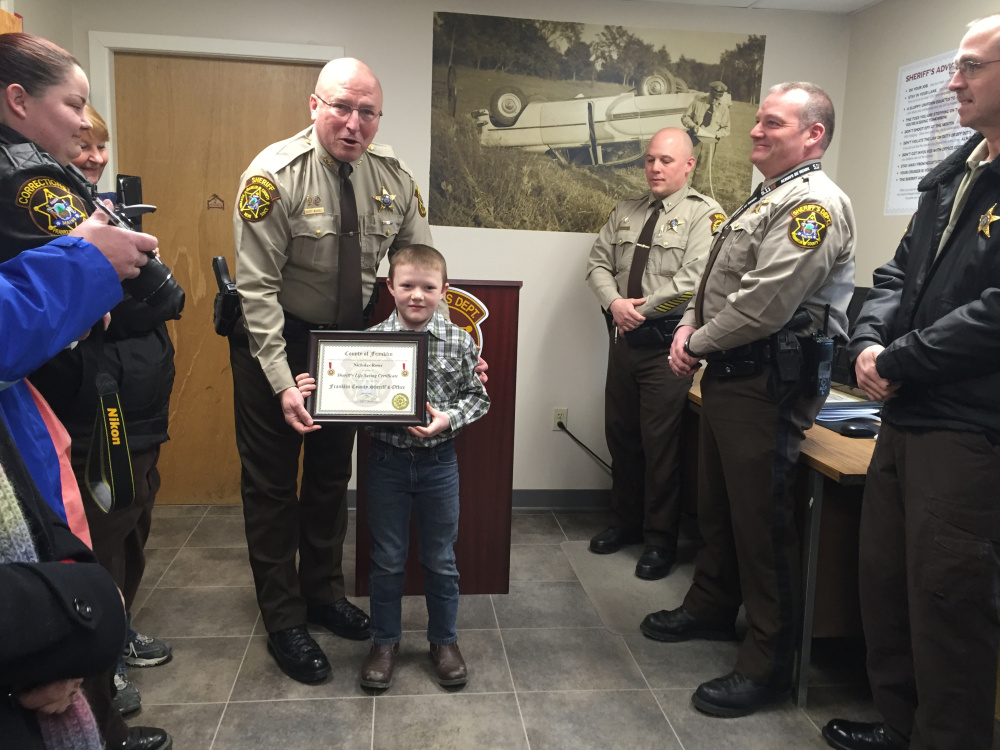 Franklin County Sheriff Scott Nichols gives Nicholas Rowe, 9, a Life Saving Certificate, Friday, for his role in helping save the live of trucker Charles Bolduc, who was shocked by electric wires on Rowe’s grandparents’ farm in New Vineyard in December. Rowe ran and got his uncle, who was recently certified in CPR, while Rowe’s grandmother, Becky Lane, administered CPR.