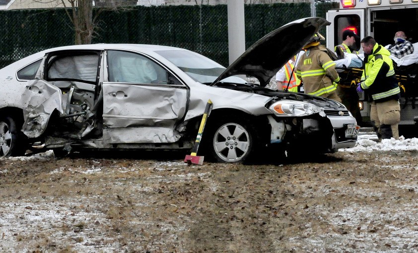 Russell Michaud is loaded into an ambulance after firefighters removed him from his car, which slid off Front Street in Waterville Monday, knocking down two light poles and coming to rest on a third pole. Police believe Michaud had a medical issue that led to the crash.