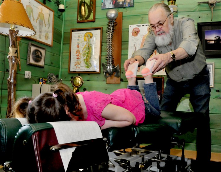 Chiropractor Ed Dunton works on client Natalie Anton in his home office in Athens on Wednesday. Dunton and his wife, Jodi-Ann, who live in Massachusetts, began practicing in their vacation home in Athens on weekends because of local need and now plan to move to the town.
