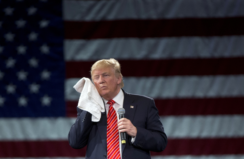 Republican presidential candidate Donald Trump wipes his cheek as he listens to a question from an audience member at a campaign event in Tampa, Fla., Monday.