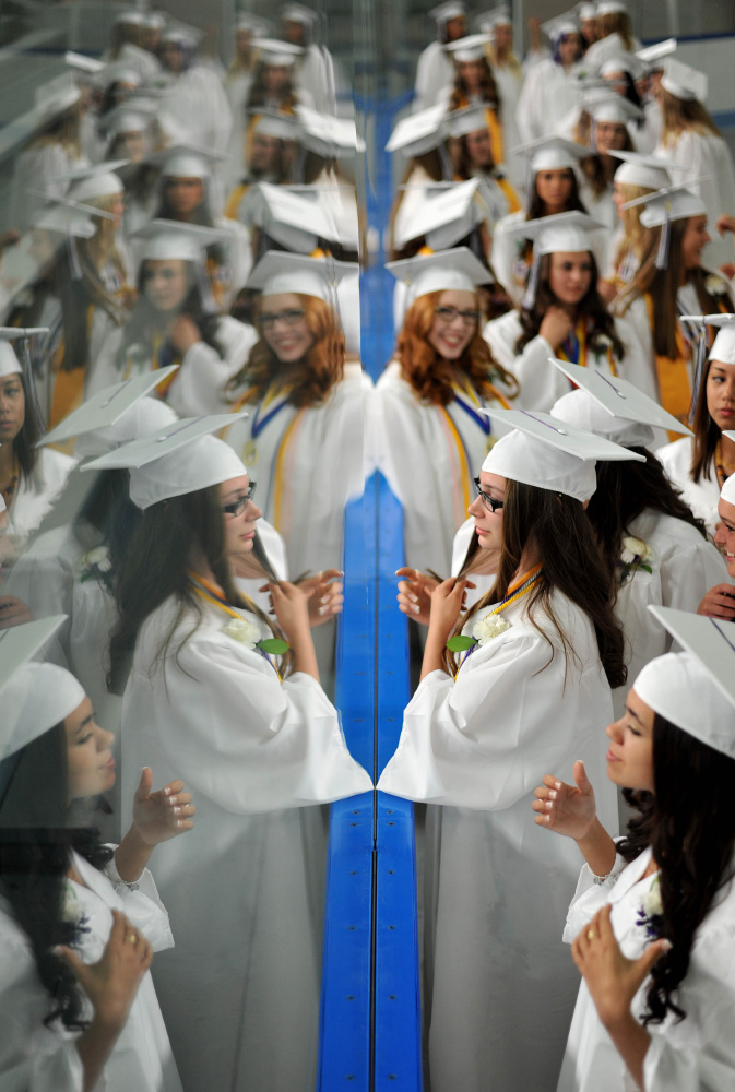 Waterville Senior High School graduate Karlie Nabarowsky, bottom center, fixes her hair in the glass at Alfond Arena at Colby College in Waterville last June. This year the girls and boys will both wear purple.