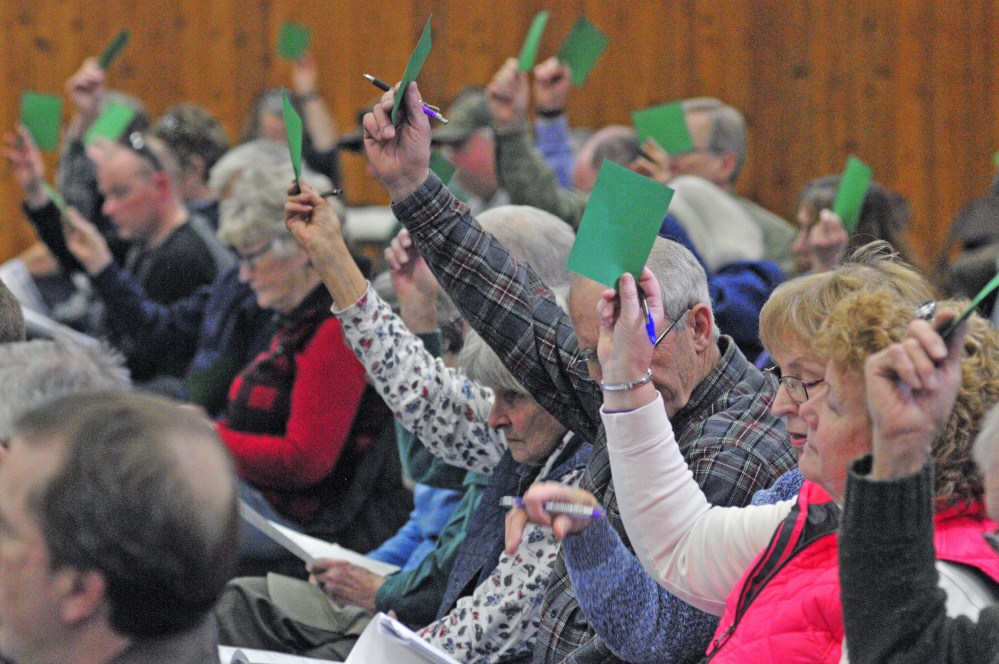 Belgrade residents hold up cards to cast votes Saturday on warrant articles during Town Meeting in the Center For All Seasons.