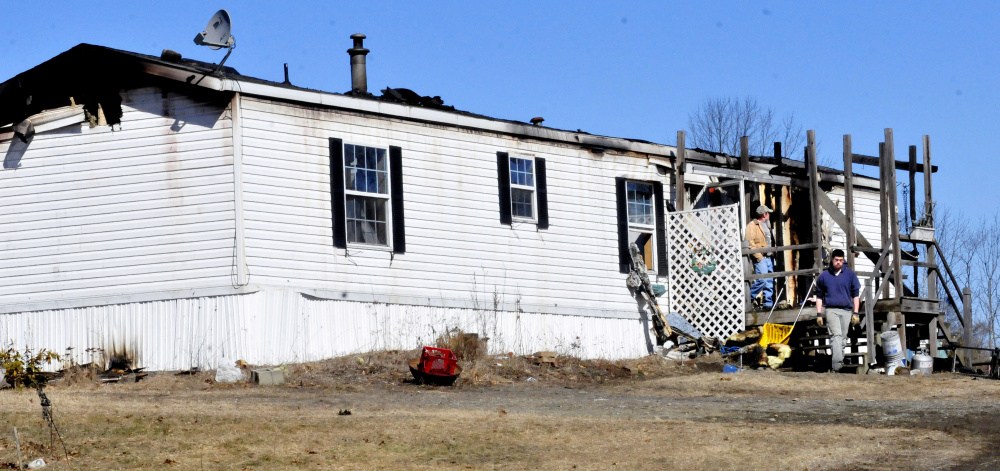 Two men exit the burned remains of a mobile home on Trafton Road in Oakland on Sunday, a day after fire destroyed the home. The man at right said they were salvaging any items that were not destroyed.