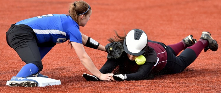 University of Maine at Farmington runner Margaret Fogarty takes a ball to the face as she dives back to second base before Colby College's Katie McLaughlin (2) can apply the tag  during a non-conference game Wednesday in Waterville. The Mules swept a doubleheader in the first games on their new field.