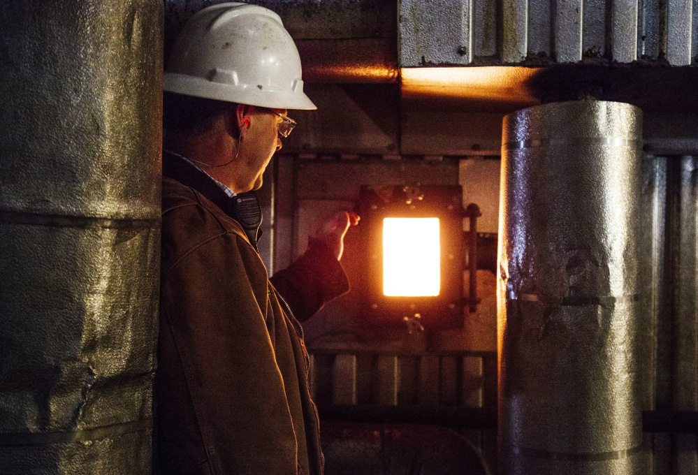 David Ettinger of ReEnergy Holdings opens a window into the biomass plant in Livermore Falls. The plants use waste wood to generate about a quarter of the state’s electricity.