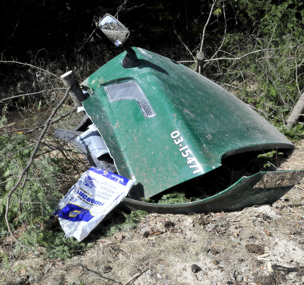 The hood of a Poland Spring Water Co. truck lies in the mud Wednesday along Route 27 in New Vineyard. Many truck parts and broken trees littered the shoulder of the road in the accident, which happened at 12:54 a.m. Wednesday.