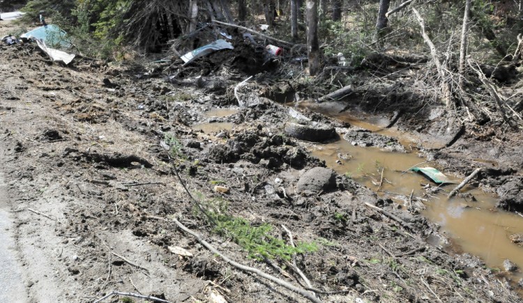 Large truck parts litter the Route 27 highway shoulder Wednesday in New Vineyard after a Poland Spring Water Co. truck went off the road and gouged a long swath in the shoulder, cut off trees and plowed up soil. The accident happened at 12:54 a.m.