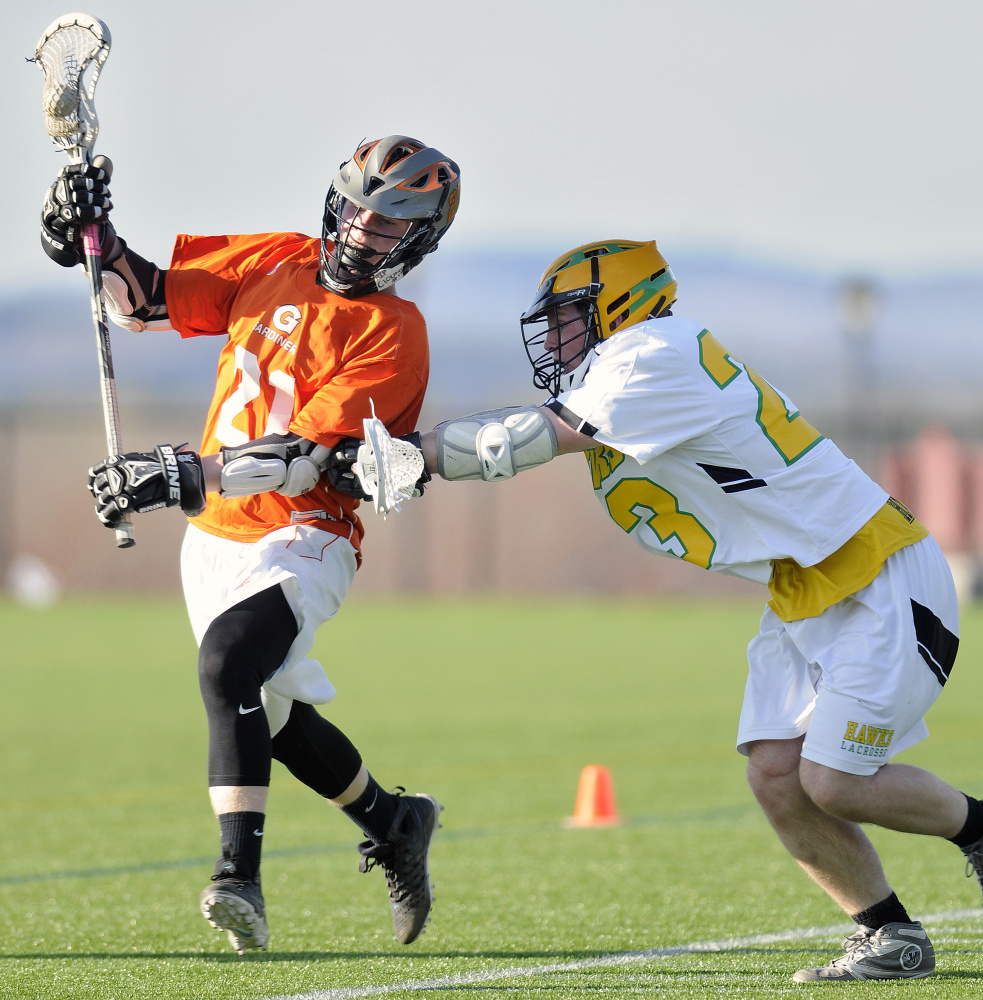 Gardiner Area High School's Sloan Berthiaume, left, gets checked by Maranacook Community High School's Drew Davis during a boys lacrosse game Tuesday in Readfield.