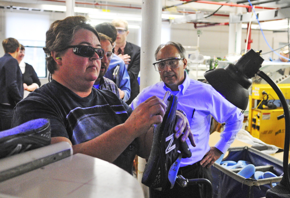 Working under UV lights, a New Balance worker spreads glue on a 950 shoe as U.S. Rep. Bruce Poliquin, R-2nd District, watches last year during a tour of the shoe manufacturing factory in Norridgewock. Poliquin is one of the representatives behind legislation that will force the military to comply with the requirement that it buy U.S.-made shoes for recruits. New Balance says it manufactures a shoe that meets the military's standards.