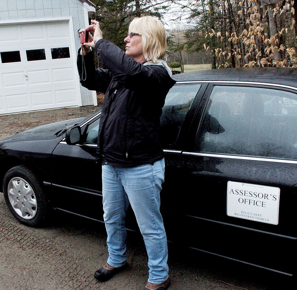 Sheryl Clifford, of Vision Government Solutions, photographs the exterior of buildings Monday at a residence in Skowhegan. The town is undergoing a revaluation of all residential and commercial properties.