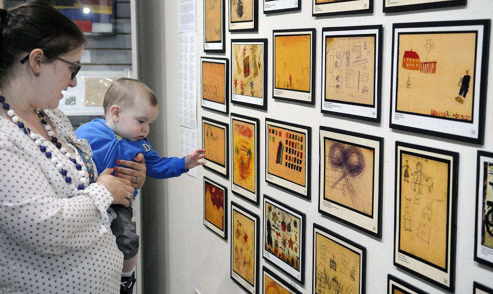 Danna Hayes and her son, Eli, seven months old, examine art on Monday that was created by children during the Holocaust at the exhibit "Those People ... Well, They're Not People at All: Children's Reactions to the Holocaust," displayed in the Holocaust and Human Rights Center of Maine in Augusta. The elder Hayes, of Bath, is the granddaughter of Holocaust survivors.
