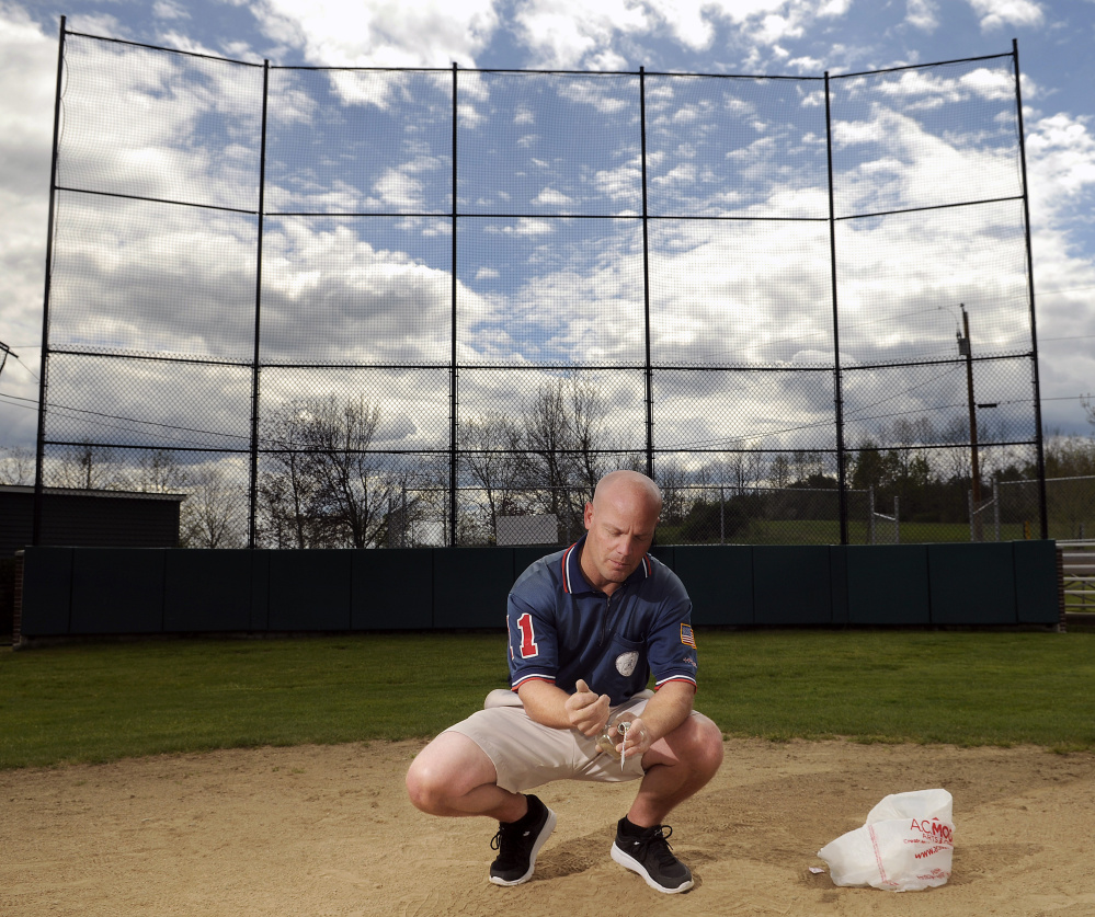 Keith Gleason collects sand from home plate at McGuire Field on Thursday in Augusta. The backstop is being dedicated in the memory of Gleason's father, Evan, who umpired at the plate for several decades.