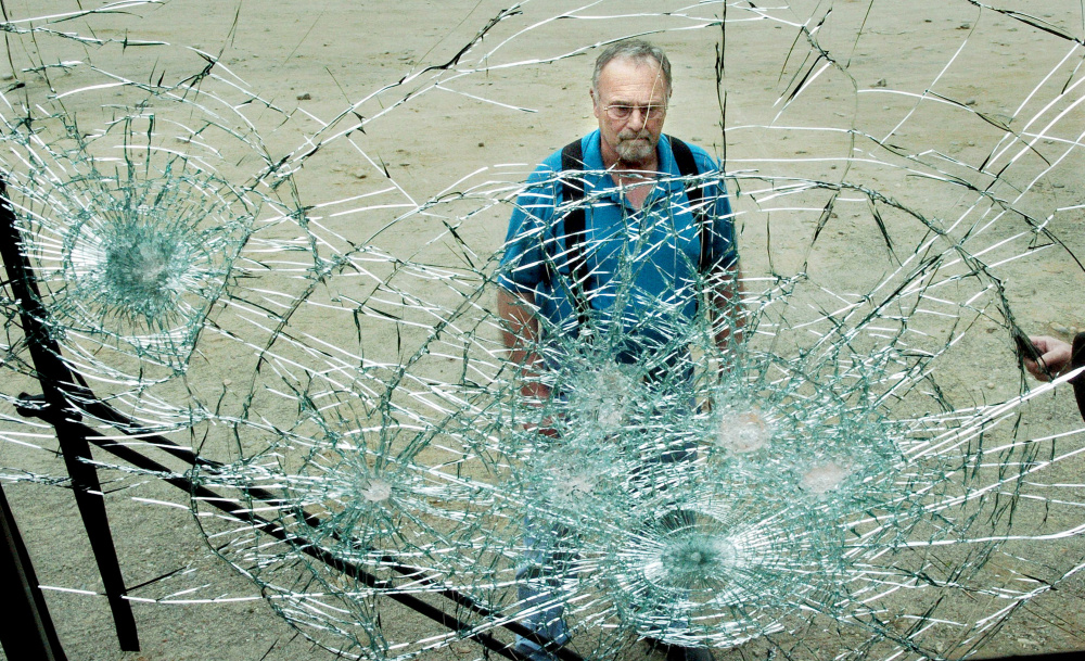 SAD 54 Transportation Director Gary Stafford surveys the smashed windshield of a district bus at the bus garage on Tuesday. Eight buses were vandalized over the weekend.