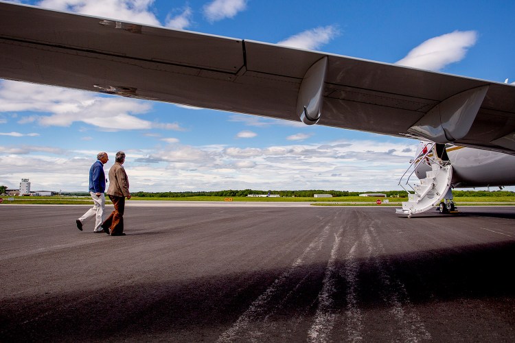 Al Caruso, owner of Mac Air Group, and Pat Reed, in charge of sales and marketing for QJets, a subsidiary of Mac Air Group, walk to one of the company's aircraft at Mac Air Group's headquarters across the tarmac from the Portland International Jetport. QJets will offer a timeshare type program to purchase one-sixth of a Hawker 1000 to be owned by a corporation or individual.