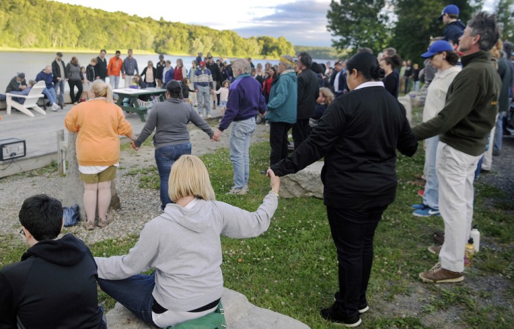 People hold hands on Monday during a vigil in Hallowell for victims of the shooting in Orlando.