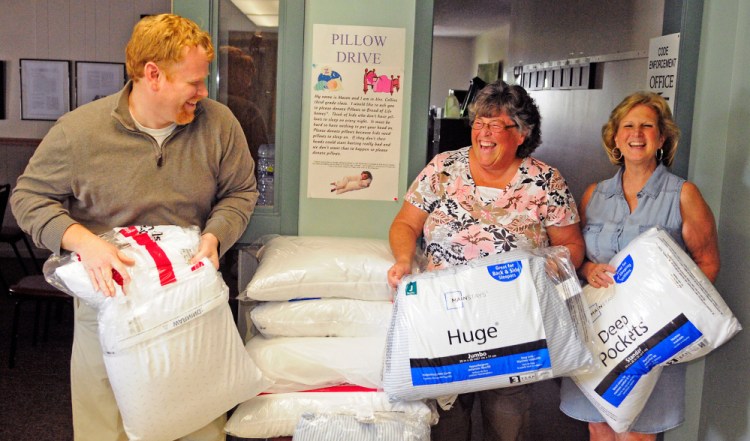 Selectman Jeremy Pare, left, Ann Young, treasurer, and Debbie Southiere, deputy clerk, joke about having a pillow fight as they pose with pillows June 9 at the Manchester Town Office. They're helping coordinate a pillow drive for the Bread of Life Ministries that was inspired by Pare's son Mason Pare.