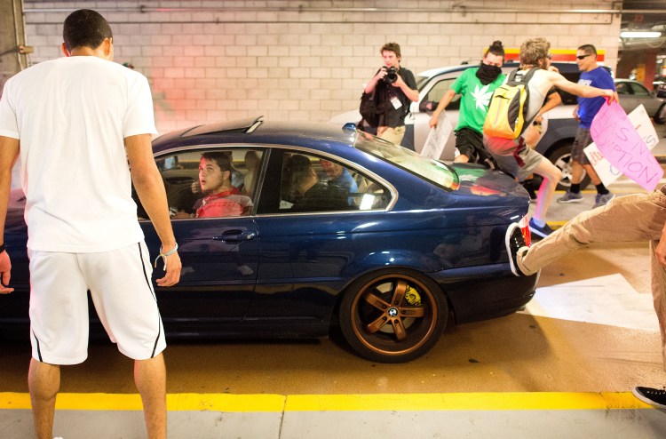 Protesters against Republican presidential candidate Donald Trump kick and jump on a car leaving a Trump campaign rally on Thursday in San Jose, Calif. A dozen or more people were punched, at least one person was pelted with an egg and Trump hats grabbed from supporters were set on fire on the ground. The Associated Press