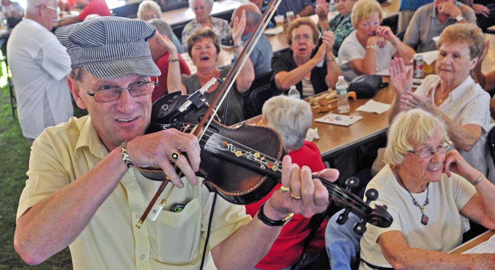 Fiddler Don LeBlanc, of the La Famille LeBlanc band, walks through the crowd playing at the start of the Festival de la Bastille on July 11, 2014 in Augusta.