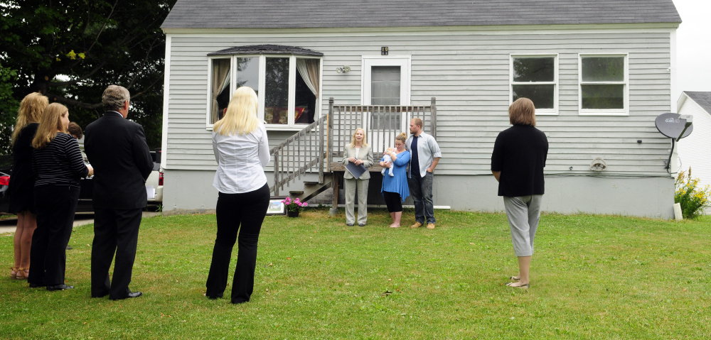 Virginia Manuel, state director of USDA Rural Development, stands with homeowners Abby and Steve Utrecht and baby Remington during a news conference Friday in Richmond.