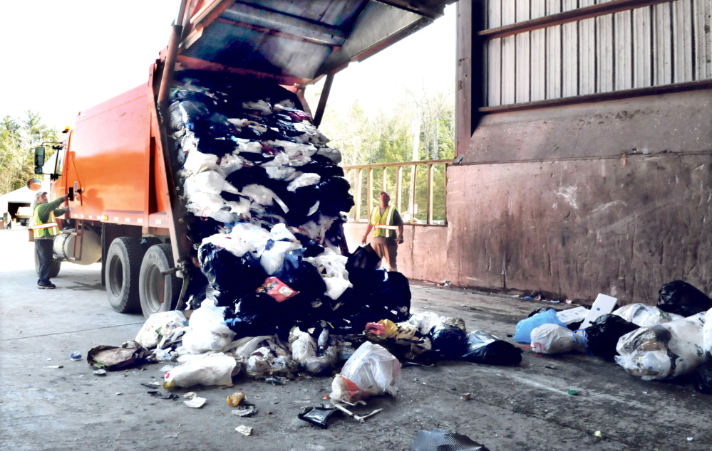 Waterville Public Works employees Brian Ames, left, and Larry Colson watch as a city garbage truck drops a load off at the Oakland transfer station. Oakland's trash will be brought to the Fiberight plant in Hampden, which was approved by the Hampden Planning Board this week.
