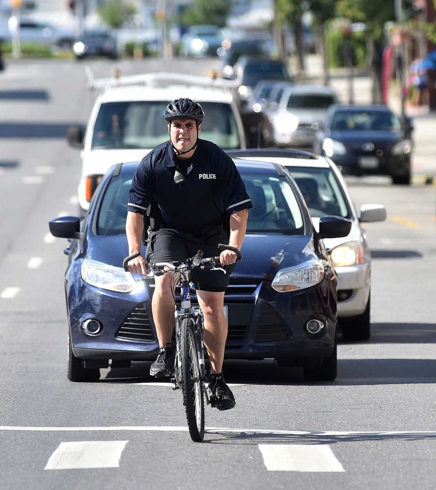 Waterville police Officer Kyle McDonald rides his police bike down Main Street in Waterville during his shift on Tuesday. It's the 16th year of the patrol, which operates mostly in the summer.