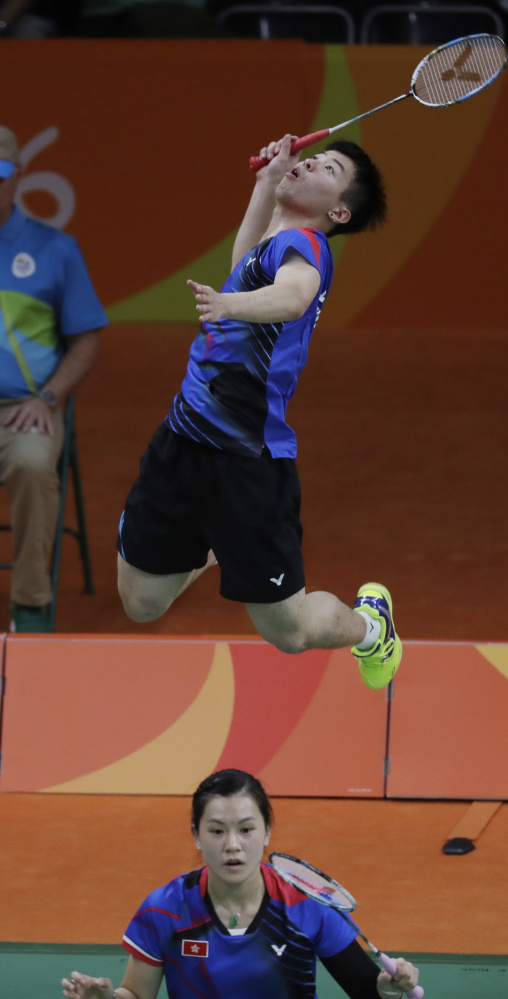 Hong Kong's Reginald Lee Chun Hei, top, returns a shot behind teammate Chau Hoi Wah during a badminton mixed doubles match. The Hong Kong team won in straight sets.