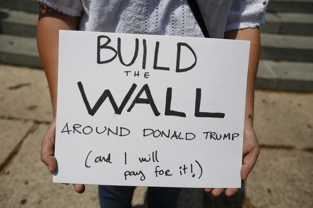 A woman demonstrating against Donald Trump's meeting with the Mexican president carries a sign during a morning protest at the Angel of Independence Monument in Mexico City that drew just a handful of people.