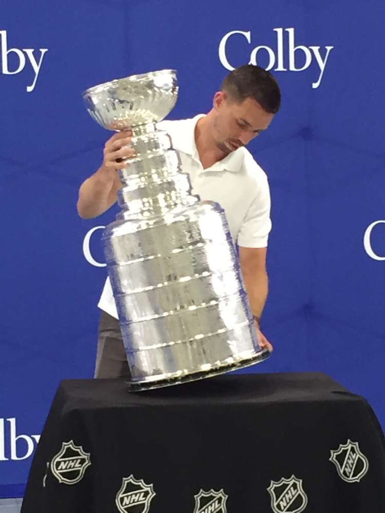 Waterville native Andy Saucier, the video coach for the Stanley Cup-winning Pittsburgh Peguins, places the Cup on a table at Colby College in Waterville on Tuesday.