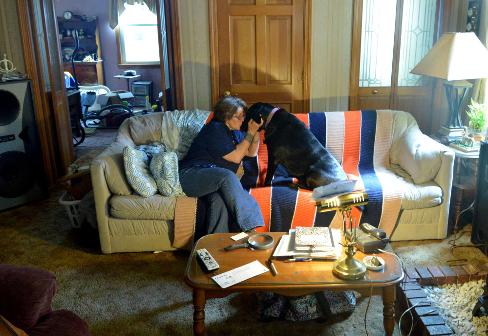 Eva St. Jean is comforted by her dog, Jasmine, as she talks about the struggle to find Waterville rental housing that will allow her to live the 80-pound black Lab mix.