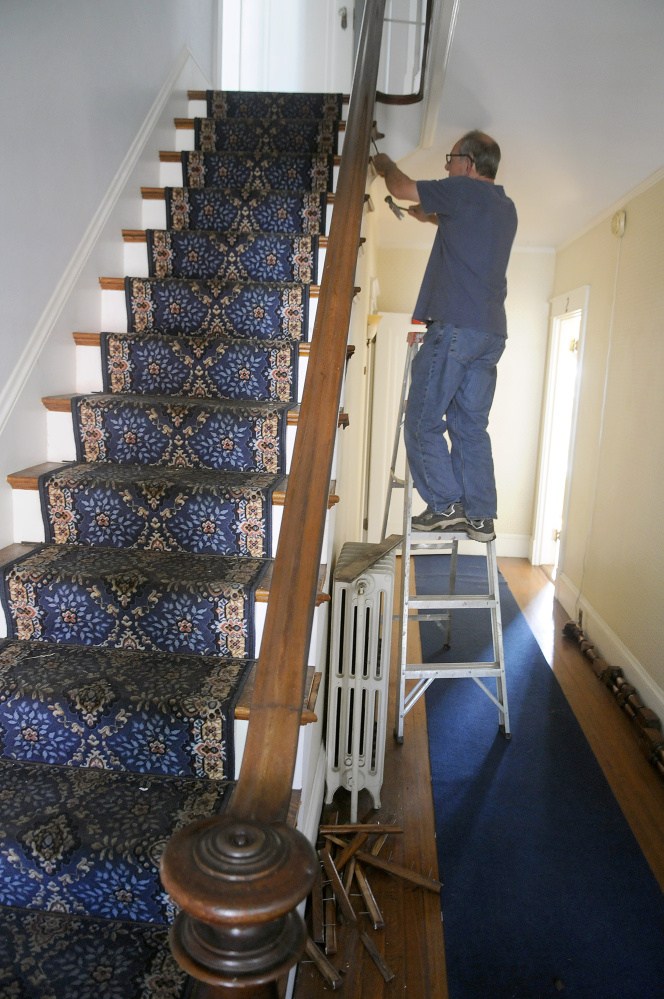Joe Carey reclaims the banister on the stairwell at 387 Water St. in Augusta on Monday. The former apartment and office building is scheduled to be demolished by Penney Memorial Baptist Church. The church plans to turn the property into a parking lot for the church, which is across East Crescent Street from the building.