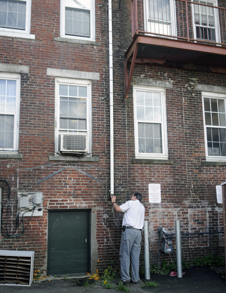 Gardiner Wastewater Treatment Director Doug Clark inspects a drain pipe Thursday on a building in the Arcade parking lot in Gardiner.