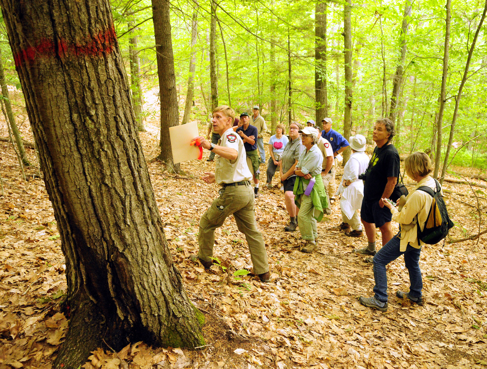 Eric Hoar, a forester with the Department of Inland Fisheries and Wildlife, left with folder, leads a tour on June 28 of areas that will be cut at Jamies Pond Wildlife Management Area in Hallowell. The timber harvesting project is set to start this coming week.