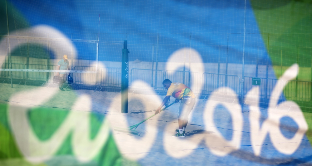 A workers rakes a court after a practice session at the beach volleyball venue on Copacabana Beach on Tuesday in Rio de Janeiro, Brazil.