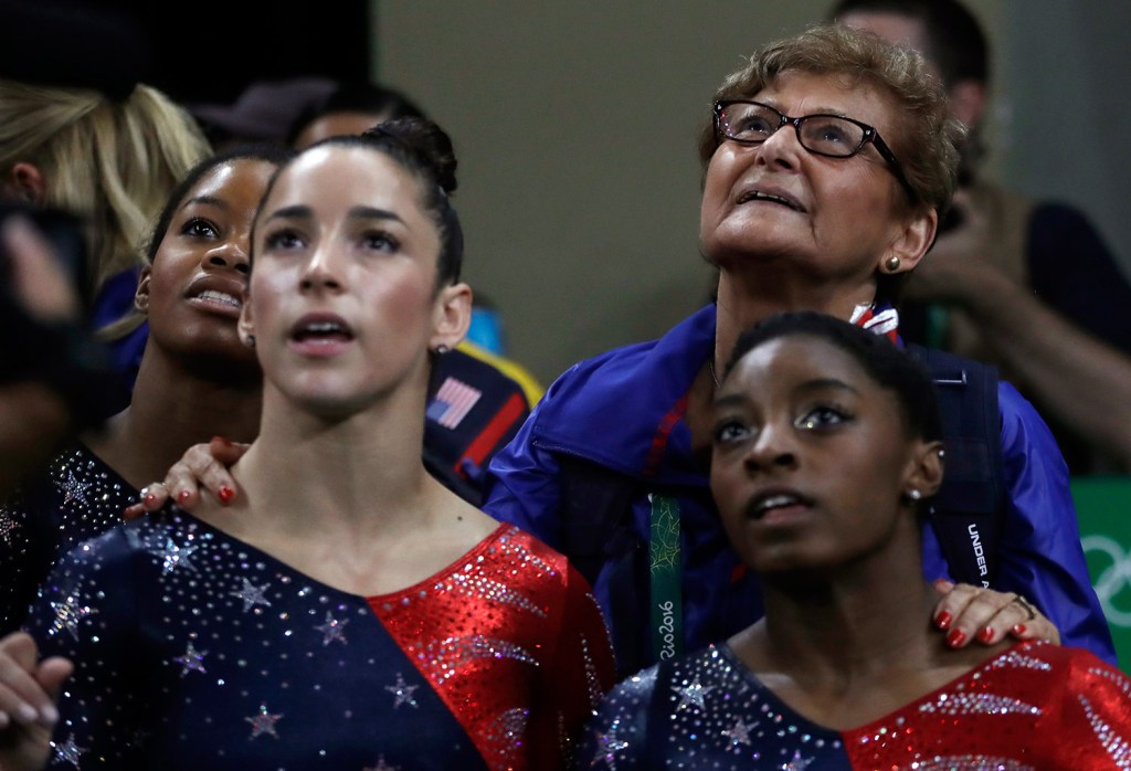 Marta Karolyi, U.S. gymnastics team coordinator, looks at the scoreboard along with, from right, Simone Biles, Aly Raisman and Gabrielle Douglas during the artistic gymnastics women's qualification Sunday.