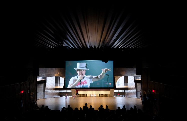 Fans watch The Tragically Hip perform live from Kingston, Ontario, at Studio Bell in the National Music Centre in Calgary, Alberta, on Saturday. (Jeff McIntosh/The Canadian Press via AP)