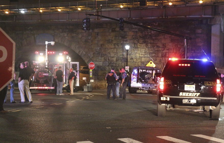 Bomb squad personnel stand around the scene of an explosion near the train station, early Monday, Sept 19, 2016, in Elizabeth, New Jersey. A suspicious device found Sunday night in a trash can near a New Jersey train station exploded early Monday as a bomb squad robot attempted to disarm it.