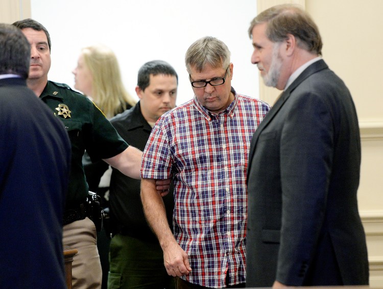 Bruce Akers, who is accused of killing of his neighbor with a machete, is led into the York County Superior Court in Alfred, where he pleaded not guilty on Tuesday.