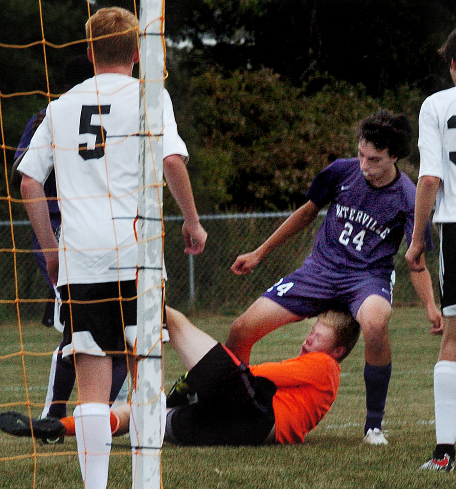 Winslow goalie Jake LaPierre covers the ball under pressure from Waterville's Ethan Nurick on Tuesday in Winslow. Winslow's Brice Hiller is at left.