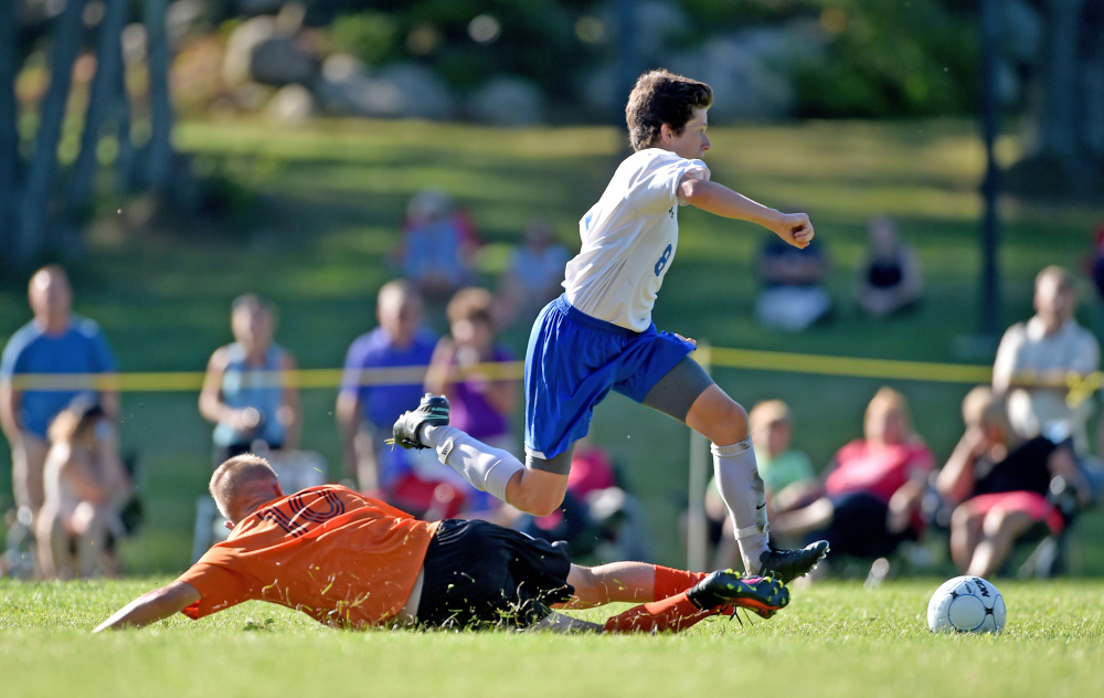 Moving on by: Messalonskee forward Jack Moore avoids a slide tackle from a Winslow defender during an Aug. 23 scrimmage in Oakland.