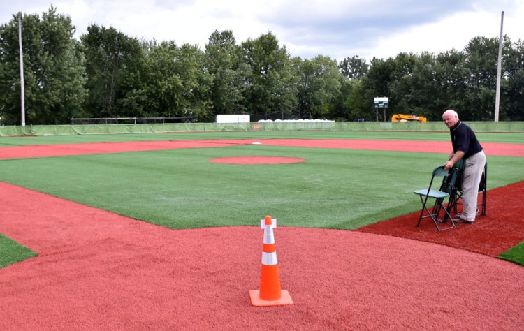 Larry Carter, right, sets up chairs along the first base line at the Wrigley Field replica at Fran Purnell Wrigley Field on Wednesday in Waterville for the field dedication.