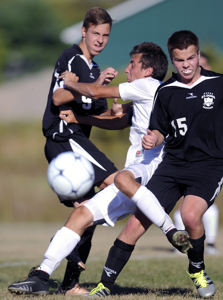 Richmond's Cody Tribbet gets sandwiched between St. Dominic's Alex Roy, left, and Hunter Emery (15)during a game Monday in Richmond.