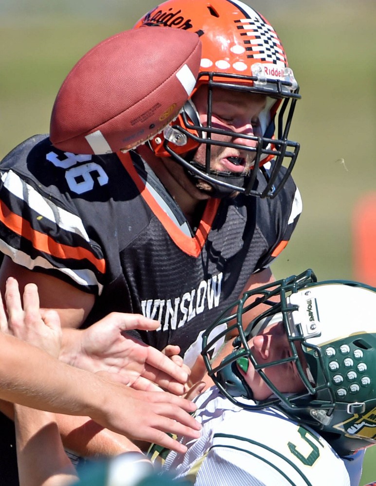 Staff photo by Michael G. Seamans 
 Mount Desert Island's Colby Lee (5) fumbles the ball as he is tackled by Winslow's Kenny Rickard (36) on Saturday in Winslow.